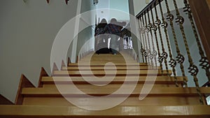 Two happy kids, boy and girl rising up the stairs with their backpacks. Siblings just back home from school. Happy