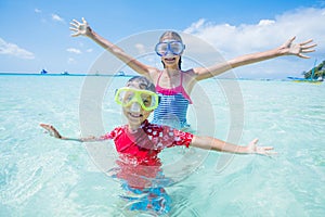 Two happy kids in diving masks having fun on the beach