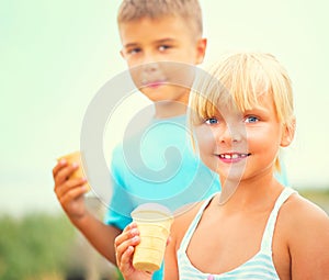Two happy kids eating icecream outdoors