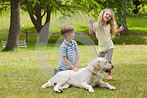 Two happy kids with pet dog at park