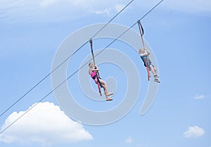 Two happy kids playing on a zip line view from below