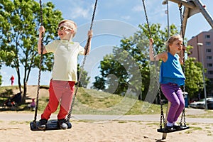 Two happy kids swinging on swing at playground