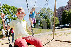 Two happy kids swinging on swing at playground