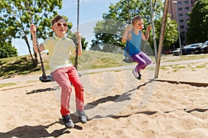 Two happy kids swinging on swing at playground