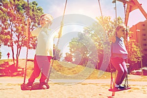 Two happy kids swinging on swing at playground