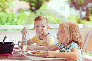 Two happy little children eating healthy breakfast at home