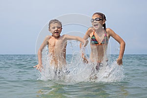 Two happy little children playing on the beach at the day time