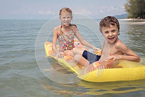 Two happy little children playing on the beach at the day time