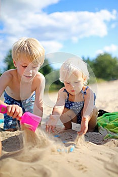 Two Happy little Children Playing in the Sand at the Beach