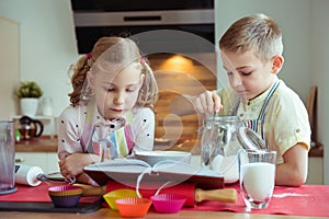 Two happy little and cute children preparing muffins in modern k