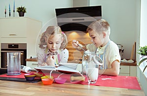 Two happy little and cute children preparing muffins in modern k