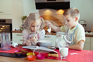 Two happy little and cute children preparing muffins in modern k