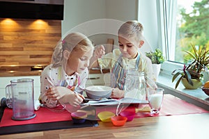 Two happy little and cute children preparing muffins in modern k