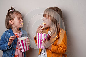 two happy little girls eating sweet popcorn