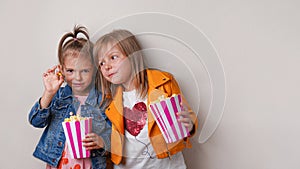 two happy little girls eating sweet popcorn with dragee