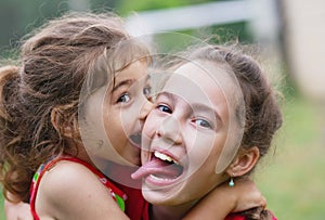 Two Happy little girls embracing and laughing at summer day