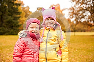 Two happy little girls hugging in autumn park