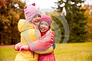 Two happy little girls hugging in autumn park