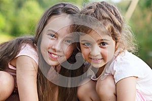 Two Happy little girls hugging at the summer park