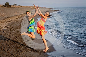 Two happy little girls jumping in the air on the beach