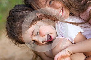 Two Happy little girls laughing and hugging at the summer park
