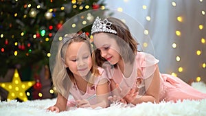 two happy little girls in pink dresses write a letter to santa claus