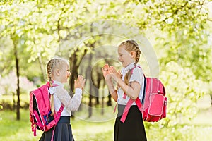 Two happy little girls playing Patty-cake outdoors