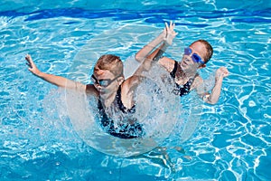 Two happy little girls playing in the swimming pool