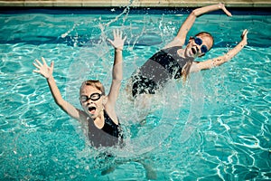 Two happy little girls playing in the swimming pool