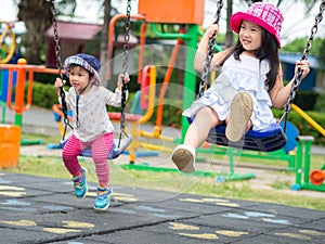 Two Happy little girls playing swing at the playground. Happy, F