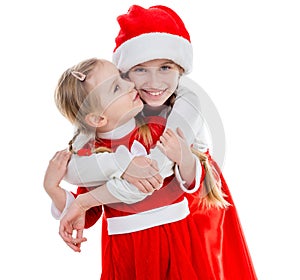 Two happy little girls in santa suits embracing