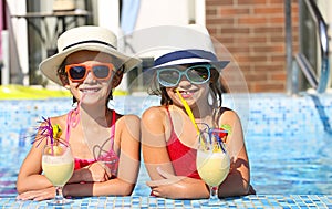 Two happy little girls in sunglasses with cocktails wearing hats