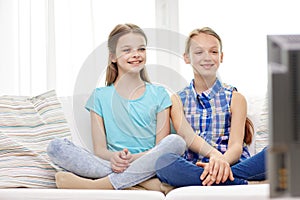 Two happy little girls watching tv at home