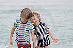 Two happy little kids boys running on the beach of ocean