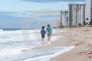Two happy little kids boys running on the beach of ocean. Funny cute children, sibling and best friends making vacations