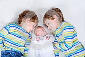 Two happy little preschool kids boys with newborn baby girl