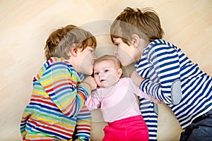 Two happy little preschool kids boys with newborn baby girl