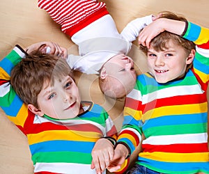 Two happy little preschool kids boys with newborn baby girl, cute sister. Siblings, twins children and baby playing