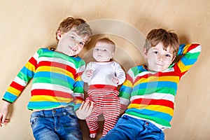 Two happy little preschool kids boys with newborn baby girl, cute sister. Siblings, twins children and baby playing