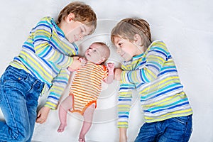 Two happy little preschool kids boys with newborn baby girl