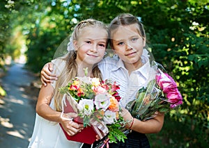 Two happy little schoolgirls with bouquets