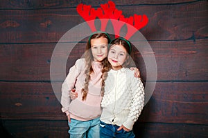 Two happy little smiling girls .Christmas concept. Smiling funny sisters in deer horns in studio.