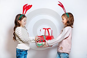 Two happy little smiling girls with christmas gift boxs..Christmas concept. Smiling funny sisters in deer horns in
