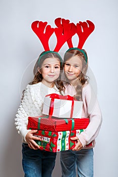 Two happy little smiling girls with christmas gift boxs..Christmas concept. Smiling funny sisters in deer horns in