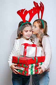 Two happy little smiling girls with christmas gift boxs..Christmas concept. Smiling funny sisters in deer horns in