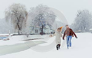 Two happy loving people are holding hands while walking along the snowy meadow. Outdoor winter portrait of couple having