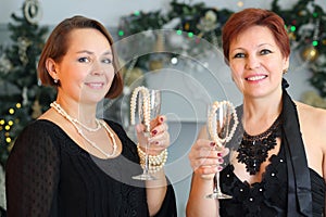 Two happy middle-aged women hold glasses with