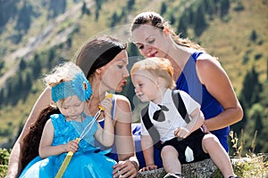 Two happy moms and children girl and boy hugging on nature