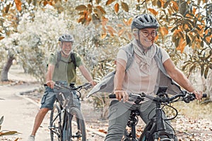 Two happy old mature people enjoying and riding bikes together to be fit and healthy outdoors. Active seniors having fun training