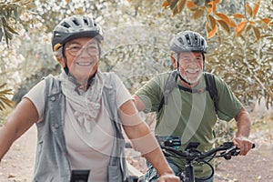 Two happy old mature people enjoying and riding bikes together to be fit and healthy outdoors. Active seniors having fun training